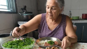 Idosa se servindo de salada verde, arroz com feijão e castanhas, alimentos ricos em magnésio